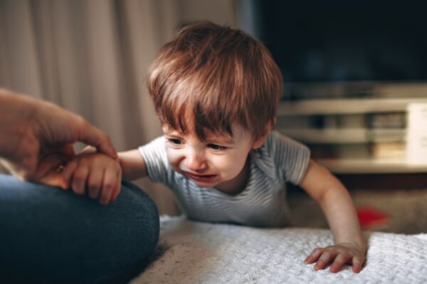 床に座っている灰色と白の縞模様のシャツを着た男の子